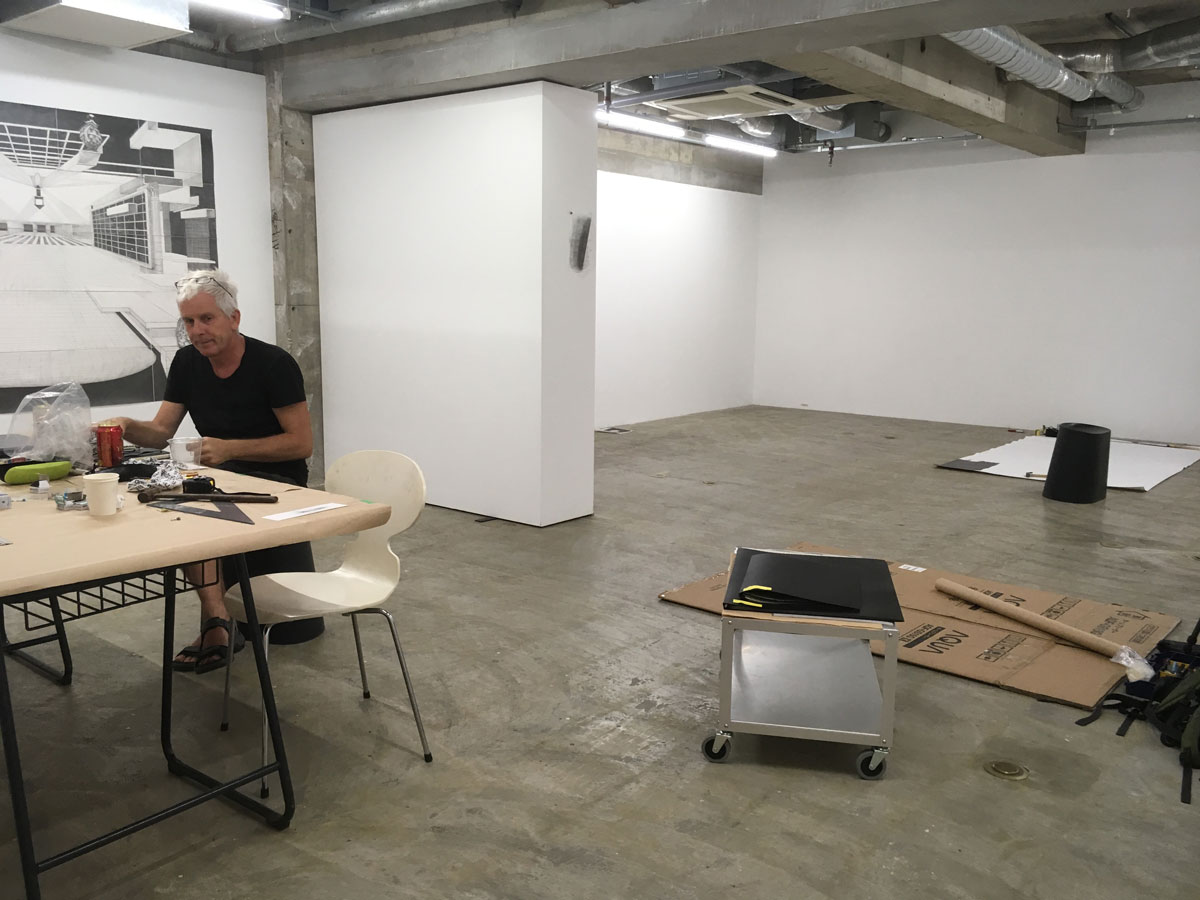 Robbie Cornelissen zit aan een tafel links. rechts op de achtergrond zijn atelier
